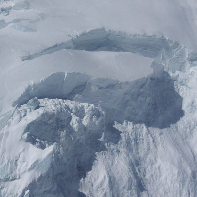Front de sérac glaciaire vu d'hélicoptère, avec une cordée en haut à gauche