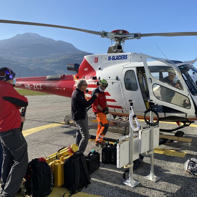 Équipe et matériel de mesure devant un hélicoptère avant une mission